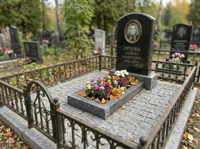 Благоустроенное захоронение с гранитной плиткой, оградой и цветником в Перми