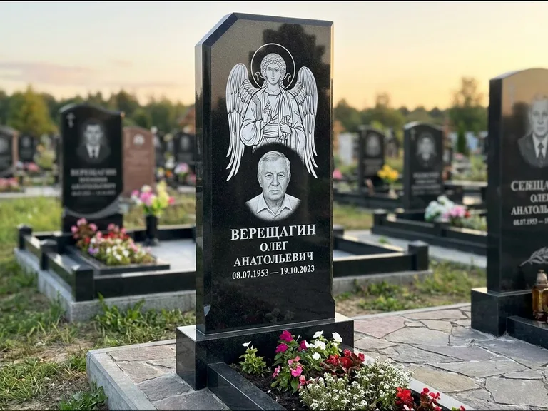 Памятник с гравировкой иконы: стела с резным навершием и нимбом в золоте — гравировка образа Спасителя, высокие разросшиеся туи полукругом, работа «Мельникова» в Перми