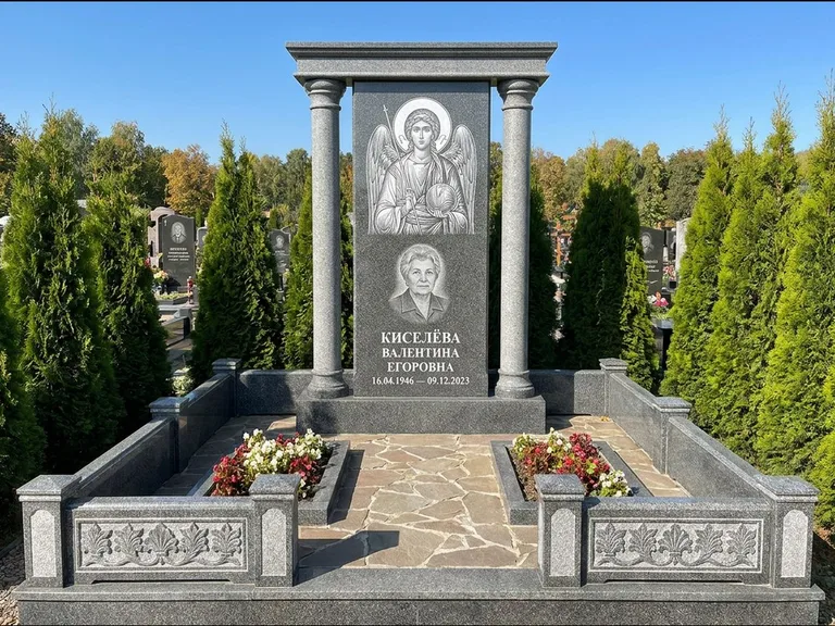 Памятник с гравировкой иконы: массивная стела с двускатным навершием-домиком — гравировка Николая Чудотворца, живая изгородь из туи, работа «Журавлёв» в Перми