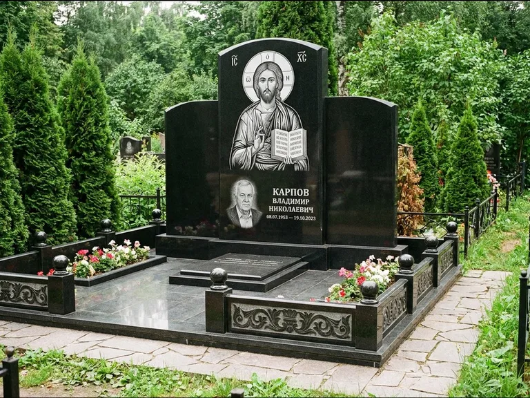 Памятник с гравировкой иконы: широкая панорамная стела с золочёным нимбом — гравировка образа Матроны Московской, цветник с белыми хризантемами, работа «Мельникова» в Перми