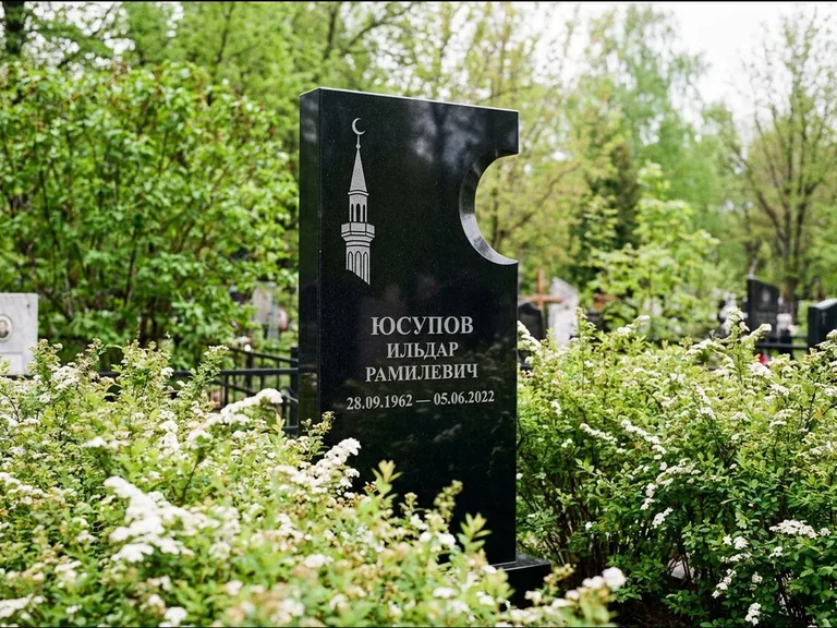 Мусульманский памятник с гравировкой мечети: стела с боковым вырезом в форме полумесяца — гравировка минарета с полумесяцем, низкие кусты спиреи в цвету, работа «Юсупов» в Перми