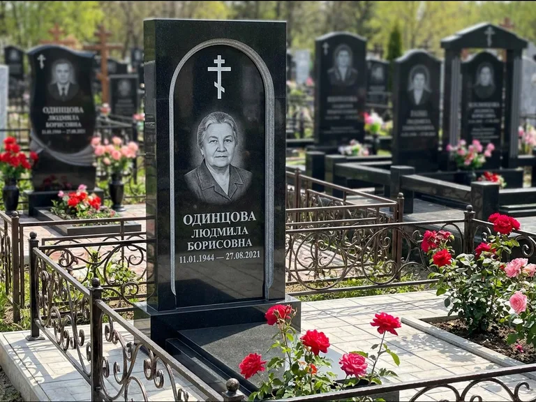 Памятник из чёрного гранита — скромная невысокая стела с крестом с терновым венцом, работа «Лаврентьева» в Перми