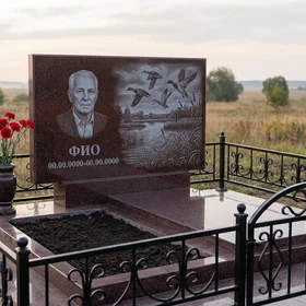 Гранитный памятник охотнику в форме арки с двустволкой